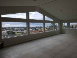 Callender's House Of Glass interior room with large panoramic windows overlooking the city and ocean