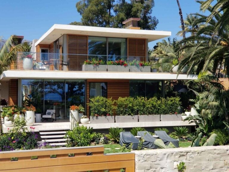 Callender's House Of Glass modern building with glass windows and sliding doors surrounded by tropical landscaping