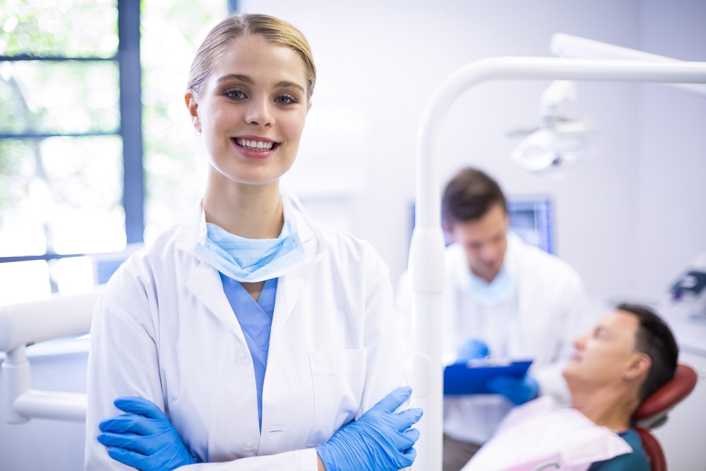 Cambrian Dental Centre smiling female dentist in a dental clinic with patients in the background