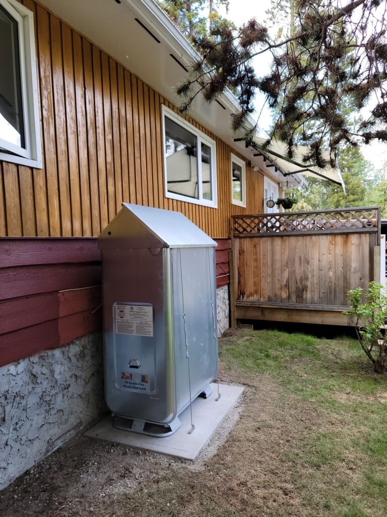 ACS Mechanical Inc outdoor installation with water heater and utility tank beside a wood-sided home