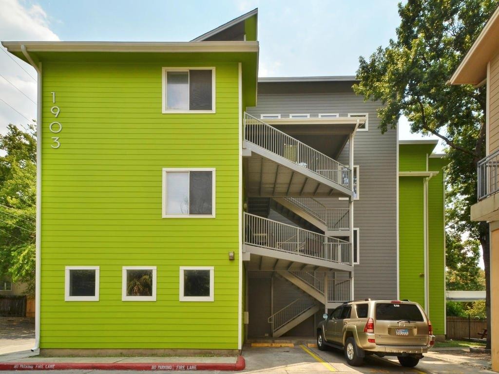Protractor Roofing residential property with green house exterior and driveway with parked SUV