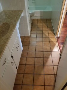 Protractor Roofing bathroom tile flooring with white vanity and toilet