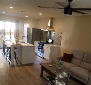 Protractor Roofing kitchen interior with white cabinetry, tile backsplash, and pendant hood ventilation
