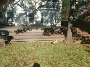 Protractor Roofing residential roof replacement with wooden deck and outdoor lawn backdrop