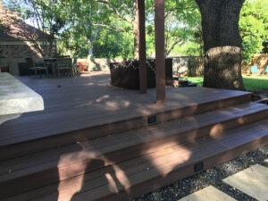 Protractor Roofing wooden deck and outdoor patio with grills and trees