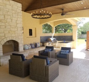 Protractor Roofing patio with stone fireplace, outdoor kitchen grill, and covered seating area