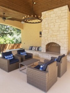 Protractor Roofing outdoor patio fireplace with stone wall and seating area