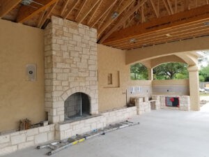 Protractor Roofing crew preparing roof framing and beams inside a new construction home with stone fireplace wall