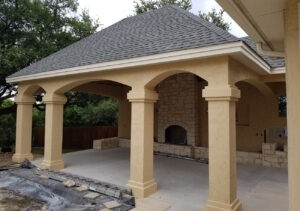 Protractor Roofing installing a shingle roof on a residential covered patio with an arched stone fireplace