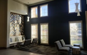 Interior of a modern office or living room with dark blue walls, large windows, and seating—Protractor Roofing