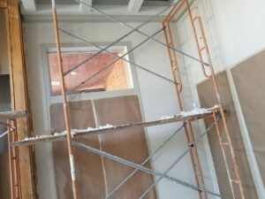 Protractor Roofing crew working on indoor construction framing with scaffolding