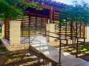 Protractor Roofing exterior photo of a stone patio and wooden pergola with railings and trees
