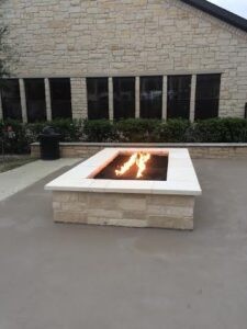 Protractor Roofing team installing a custom fire pit in a stone patio courtyard