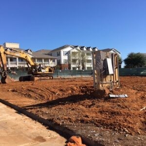 Protractor Roofing construction site with excavator preparing foundation for a new home