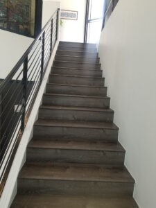 Protractor Roofing team member standing on interior stairway with railing in a modern building