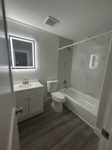 Protractor Roofing bathroom interior with bathtub, toilet, vanity sink, and shower fixtures