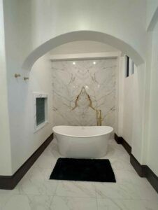 Protractor Roofing bathroom interior with arched ceiling, marble tile walls, and freestanding bathtub