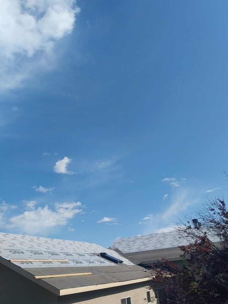 A+ Roofing Services roof installation with underlayment installed under a blue sky