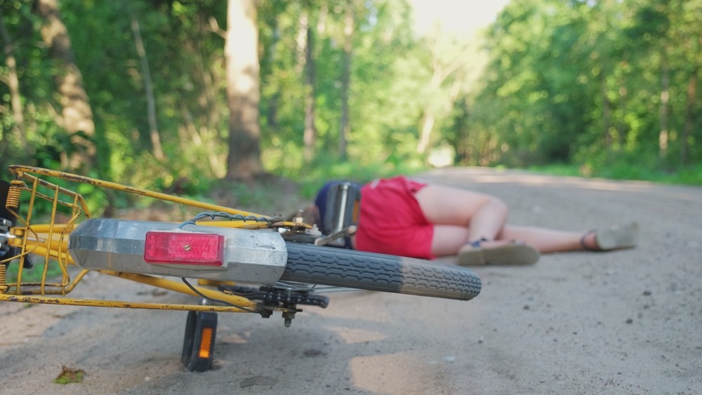 Young,Injured,Unconscious,Caucasian,Girl,Cyclist,Laying,On,Ground,Rural