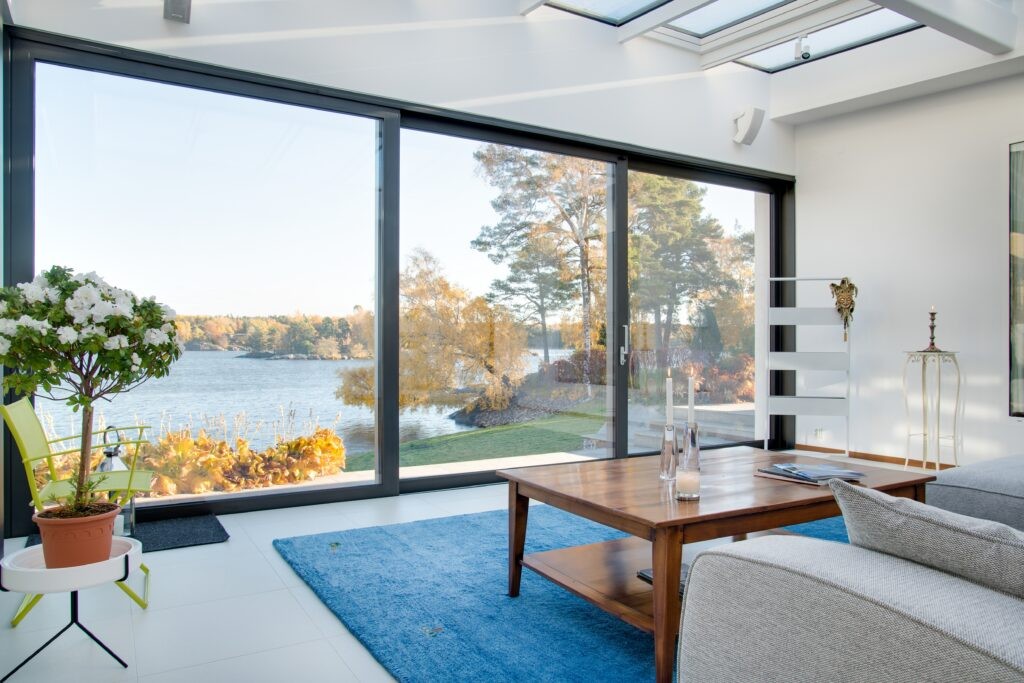 Cutting Crew Glass Inc. modern living room with large panoramic window overlooking the lake