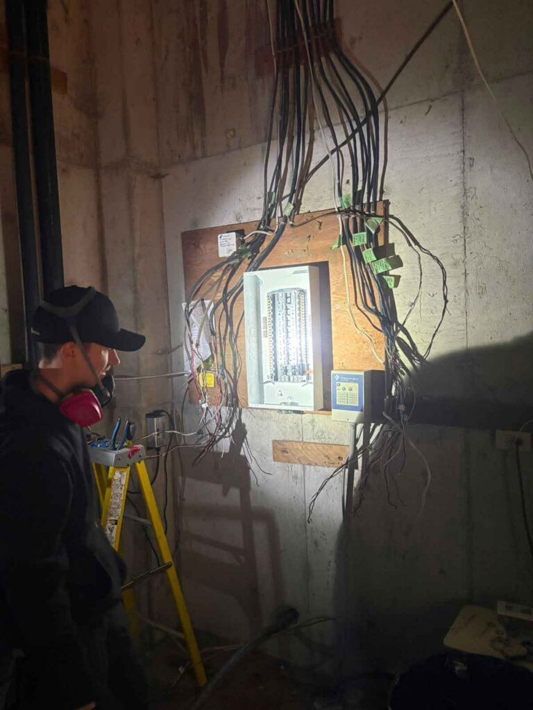Excalibur Electric Ltd electrician working on electrical panel wiring installation in a basement